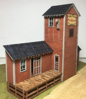 Model firehouse with red brick exterior and wooden deck on a white background