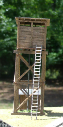 Model of a wooden observation tower with a ladder against a natural background