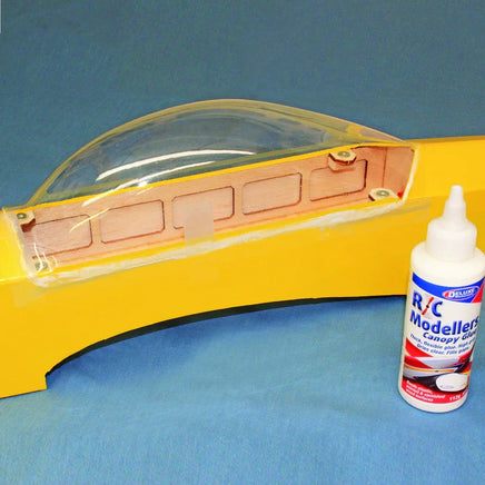 Model car canopy with a bottle of RC Modeler's glue on a blue background