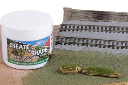 Model train track setup with a container labeled 'Create and Shape' on a white background