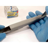 Person wearing blue gloves holding a metal object with Plastic Magic Cement box in the background.