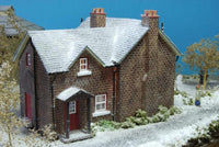 Model of a brick house with snow on the roof against a blue sky