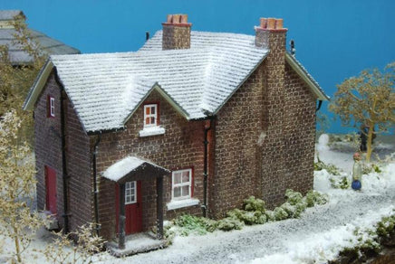 Model of a brick house with snow on the roof against a blue sky