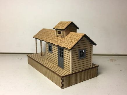 Model of a small wooden cabin with a shingled roof on a white background