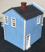 Model of a blue house with a black roof on a dark surface