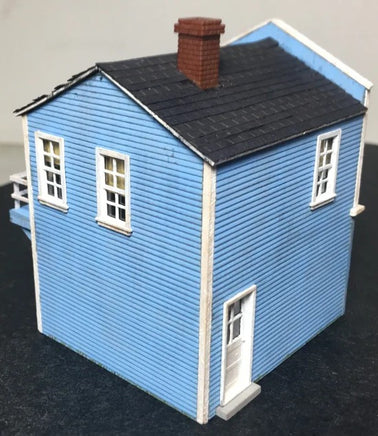 Model of a blue house with a black roof on a dark surface