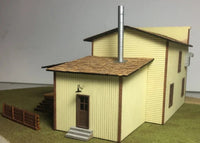Model of a two-story building with a chimney on a gray background