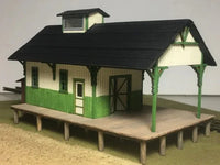 Model of a small building with a green and white exterior on a plain background