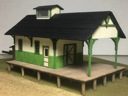 Model of a small building with a green and white exterior on a plain background