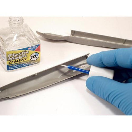 Person applying Plastic Magic Cement to a metal object with a gloved hand.