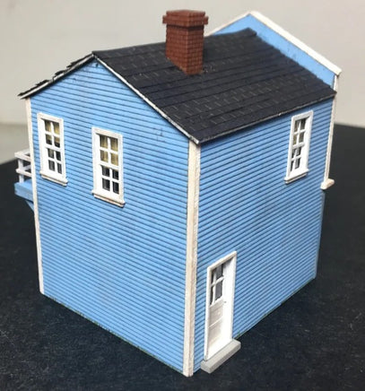 Model of a blue house with a black roof on a dark surface