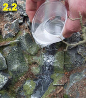 Clear plastic cup pouring water onto a rock with a natural background