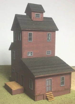 Model of a two-story building with a red brick facade and gray roof on a plain background.