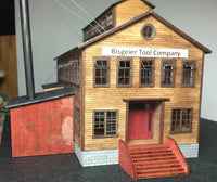 Model of a wooden building with 'Bisgeier Tool Company' sign on a gray background