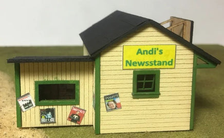 Model of a newsstand with 'Andi's Newsstand' sign on a white background