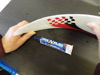 Person holding a curved object with a tube of Fix-N-Lex glue on a dark surface