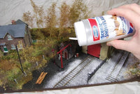 Model train setup with a hand applying snow effect spray can.