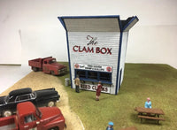Model of a clam shack with vintage trucks and people around it.