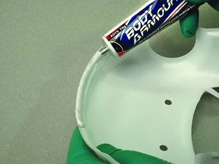 Hand applying a tube of poly bannown to a white wheel rim.