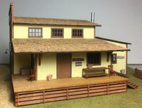 Model of a two-story building with a wooden deck and furniture on a neutral background