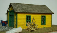 Model of a yellow building with green doors and windows on a plain background