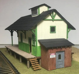 Model train station building with green and brown design on a plain background