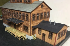 Model of a wooden building with a dock area on a dark surface