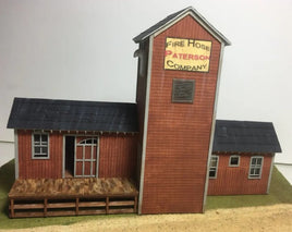 Model of a fire station with a tall tower and smaller buildings on a plain background