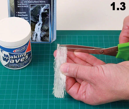 Person holding a small piece of material with scissors, next to a container labeled 'Making Waves' on a green cutting mat.