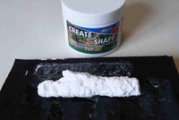 White modeling clay on a black surface with a container labeled 'Create and Shape' in the background.