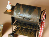 Rust-covered miniature grill with a small goose figurine on top against a plain background
