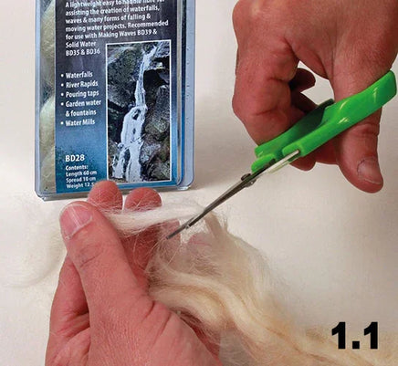 Person cutting yarn with green scissors against a white background